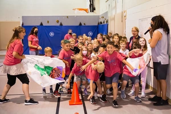 Large group of children breaking through handmade paper sign