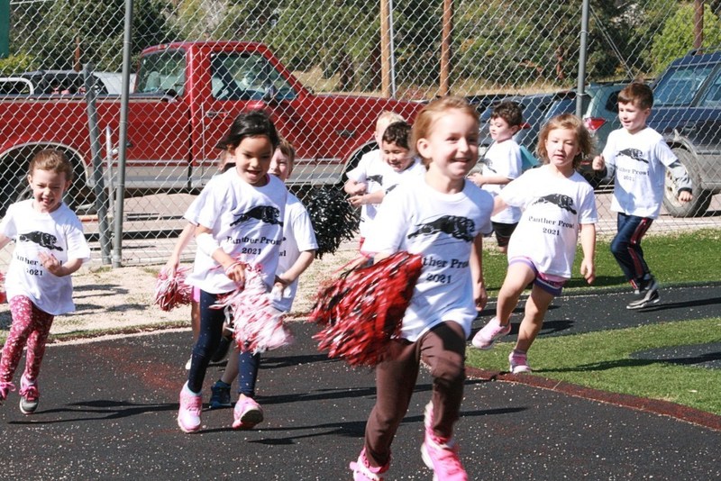 Group of children with pom poms running around school track