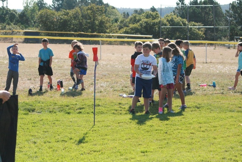 Group of children lined up on school field to play a game with a frisbee